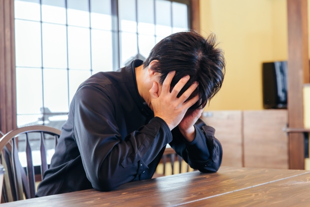 売上が安定せず悩む飲食店店長が頭を抱えている様子