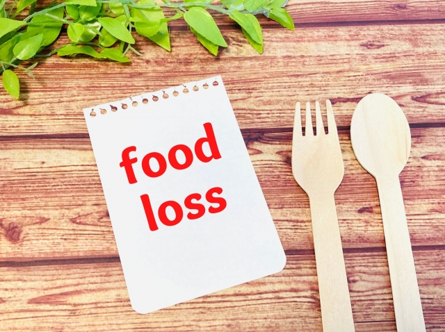 「food loss」と書かれたメモと木製カトラリー。飲食店の食品ロスや廃棄問題をイメージした写真。