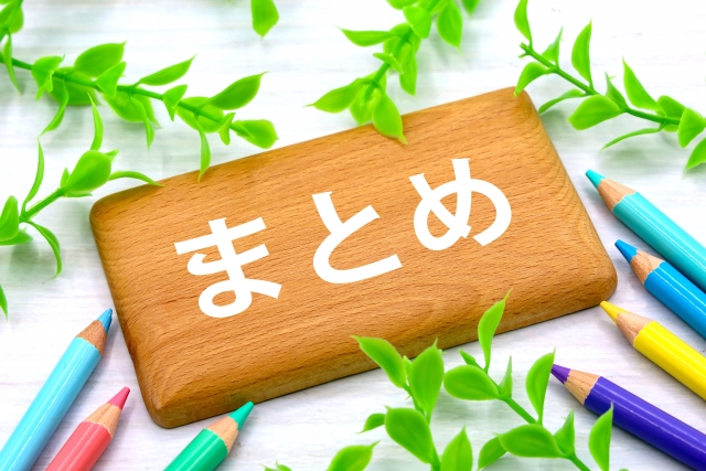 木のプレートに「まとめ」と書かれ、周囲にカラフルな鉛筆と緑の葉が飾られている写真。
