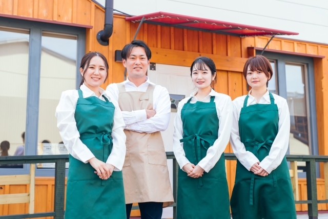 飲食店の前で笑顔で並ぶ店長とスタッフ