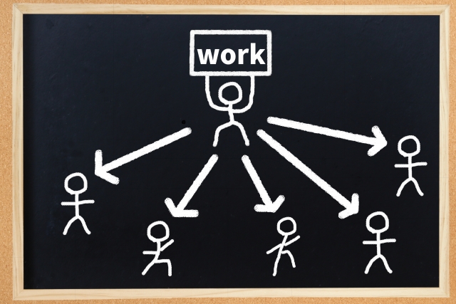 仕事をスタッフへ分担して任せる様子を描いたイラストの写真