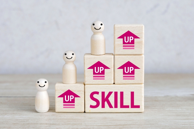SKILLとUPの文字が書かれた木製ブロックと人形、スキルアップを象徴するイメージ