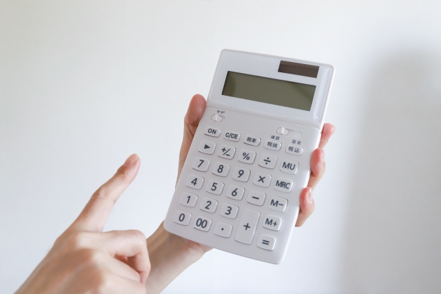 電卓を手に持ち数値を確認している様子の写真