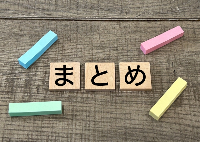 木のテーブルの上に「まとめ」と書かれた木製ブロックとカラフルな消しゴムが並んでいる写真