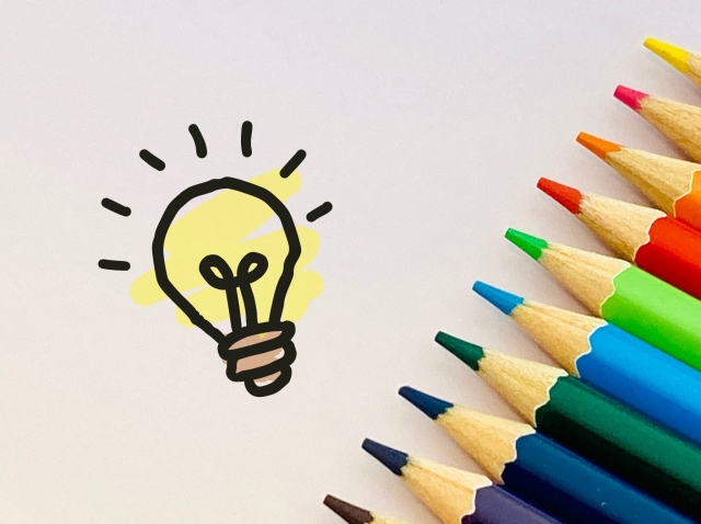 ひらめきを表す電球イラストと色とりどりの色鉛筆の写真
