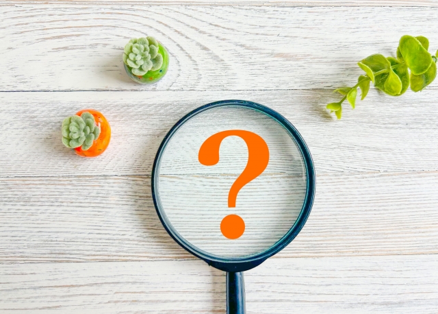 クレーム対応の原因を探るイメージとして使われる虫眼鏡と疑問符の写真