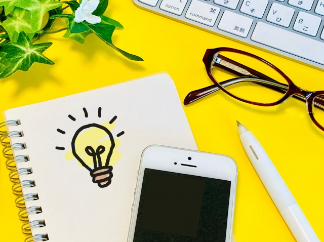 ノートとスマートフォン、眼鏡などを並べたアイデアを表すイメージ写真