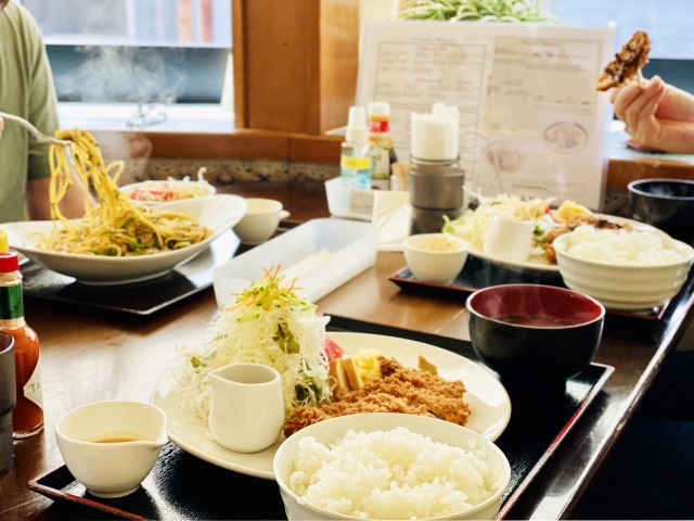 定食を提供する飲食店で複数の料理が並ぶテーブルの写真